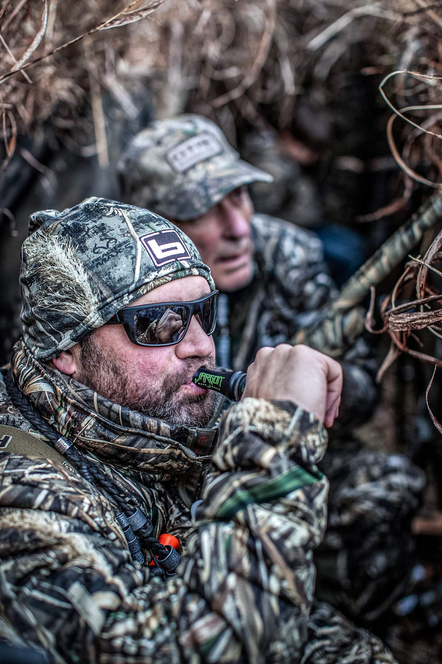 chad belding working a duck call in a blind