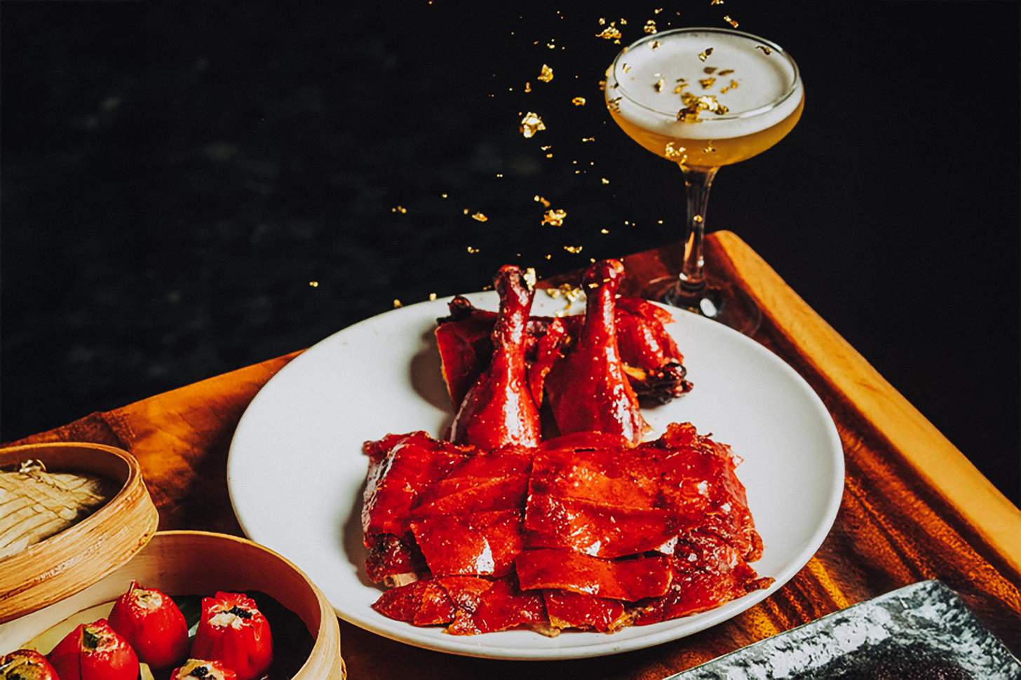 Peking Duck on a plate with a cocktail and dumplings