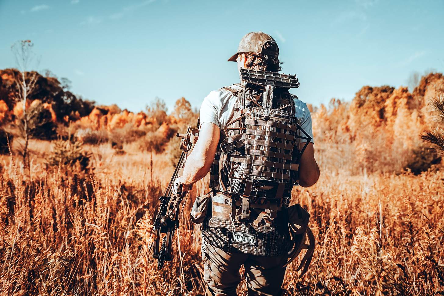 a bowhunter hiking in with his hunting saddle on his back