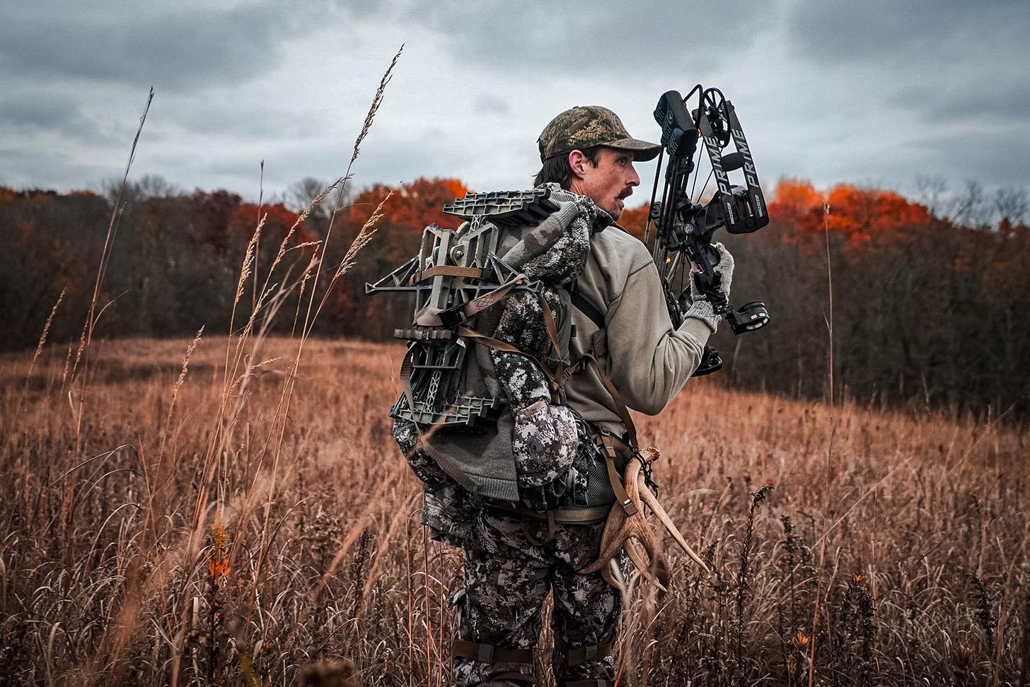 a bowhunter hiking in with his hunting saddle on his back