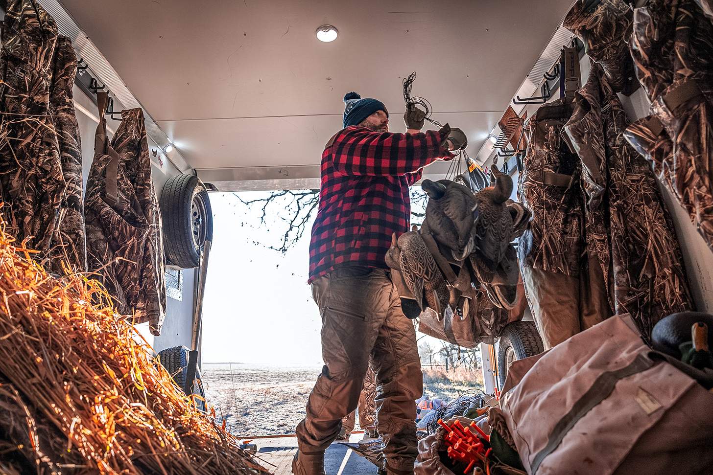chad belding in his duck hunting trailer hanging some dekes