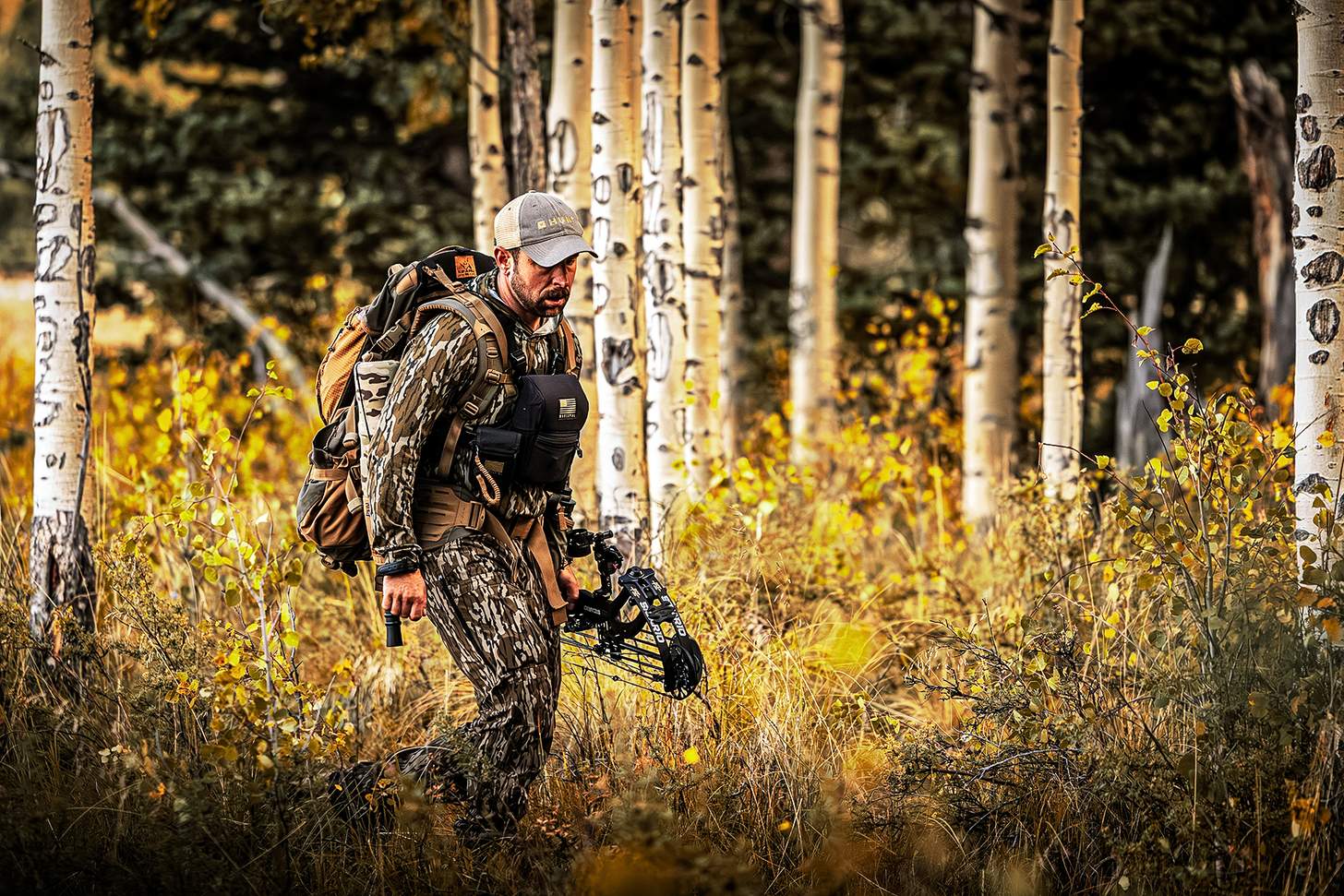 a bowhunter walking through the hardwoods