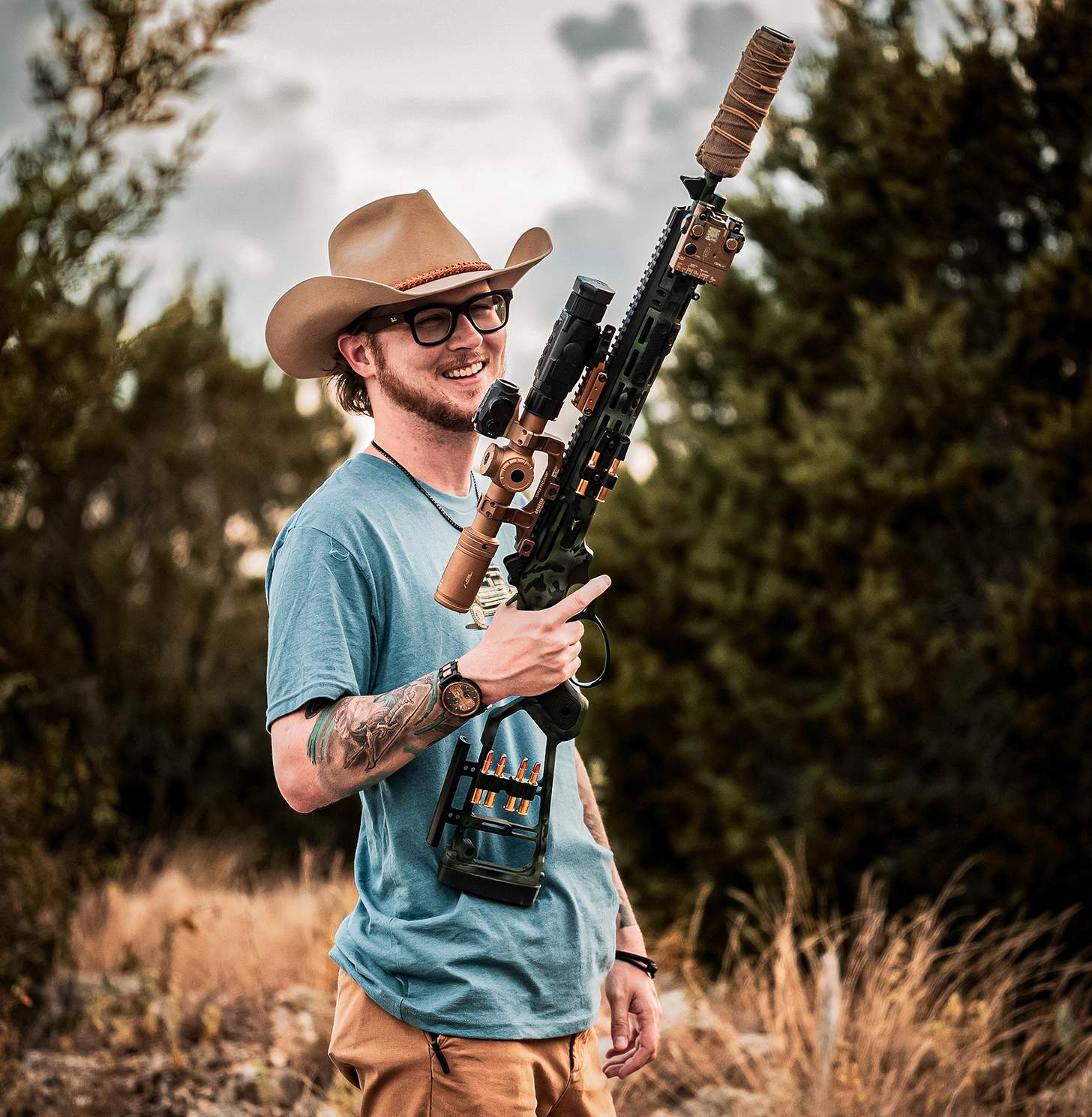 a man holding a supressed lever action rifle