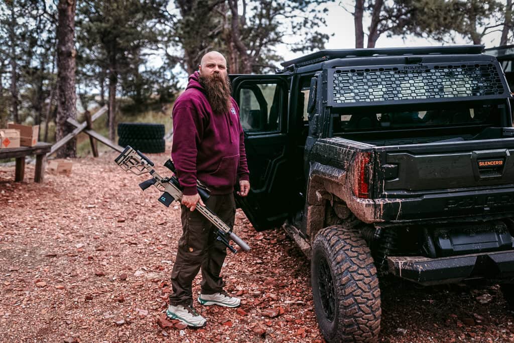 man holding a precision rifle with a SilencerCo Scythe-Ti suppressor