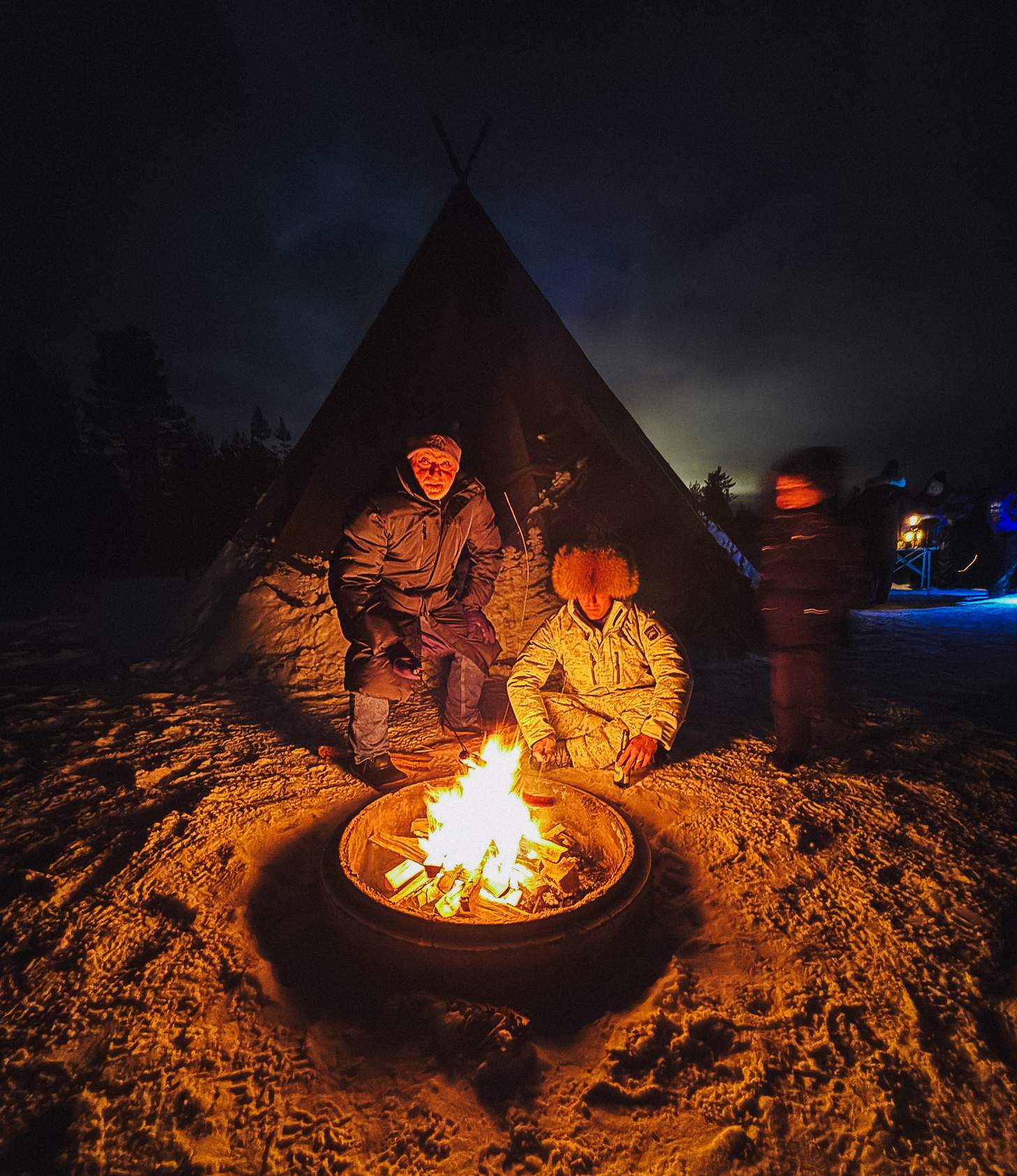 a campfire by a tend in the snow