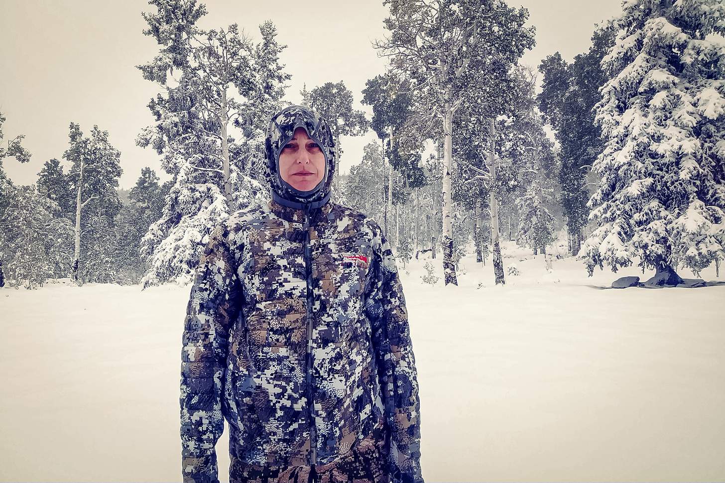 a female hunter in full cold weather hunting gear in the snow