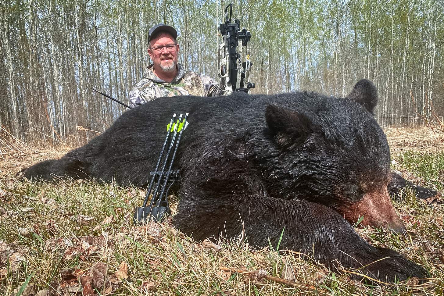 a hunter with a crossbow and a dead black bear