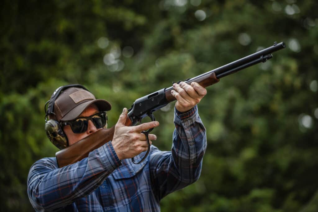 A man shoulders a lever action rifle. The Savage REVEL Classic. 