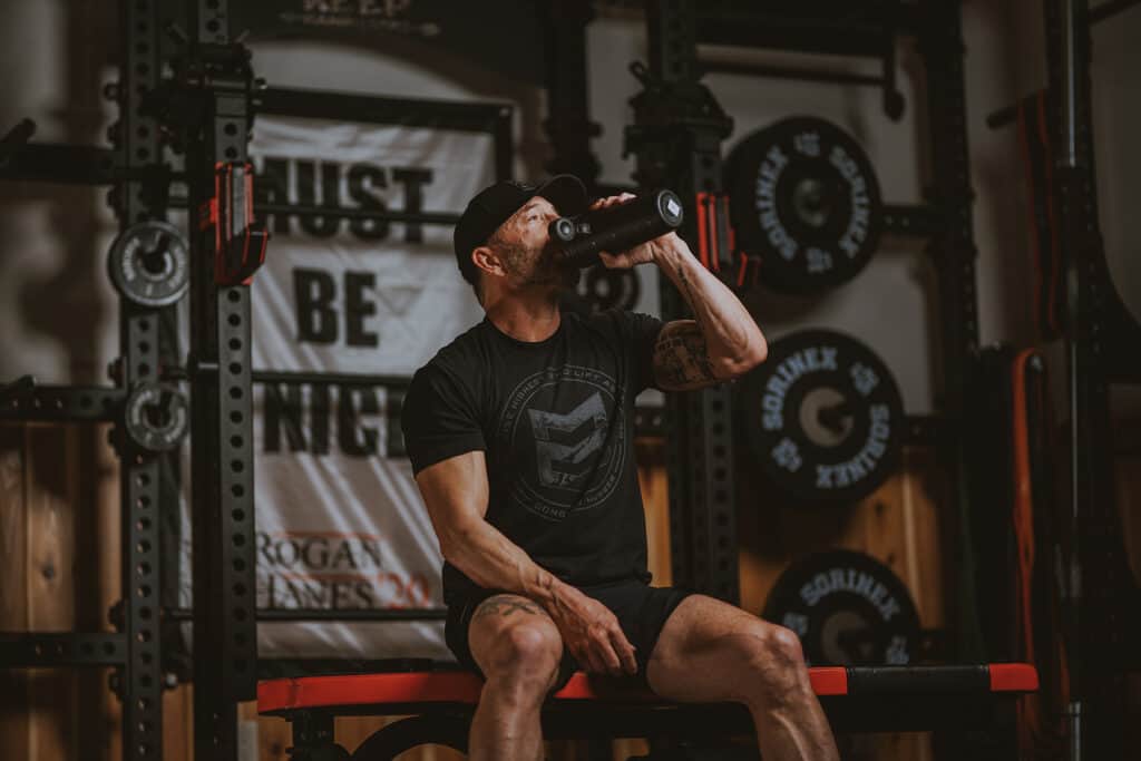 man drinking water on a weight bench