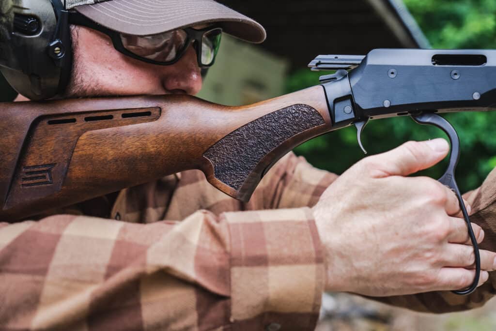 A man shoulders the Savage REVEL DLX rimfore lever action.