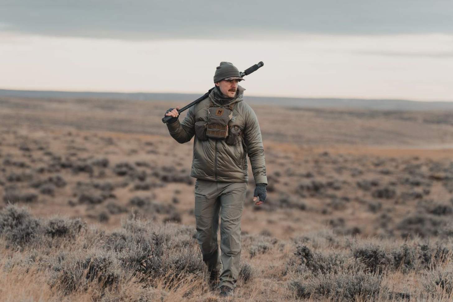 A hunter dressed Kifaru apparel walks across the prairie.