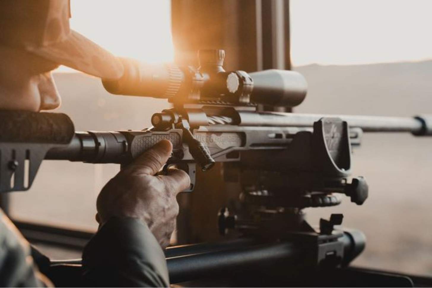 The sun sets behind a shooter aiming a Viking Armament rifle.