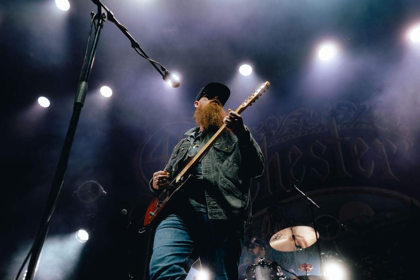 A bearded man plays guitar on stage.