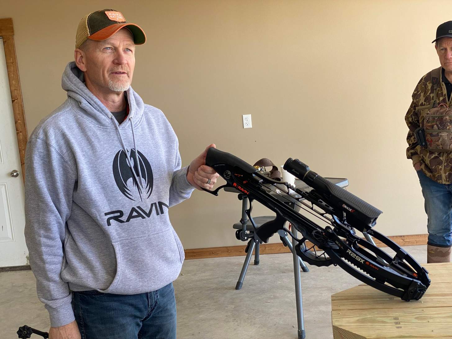 A man in a hoodie holds a Ravin crossbow.