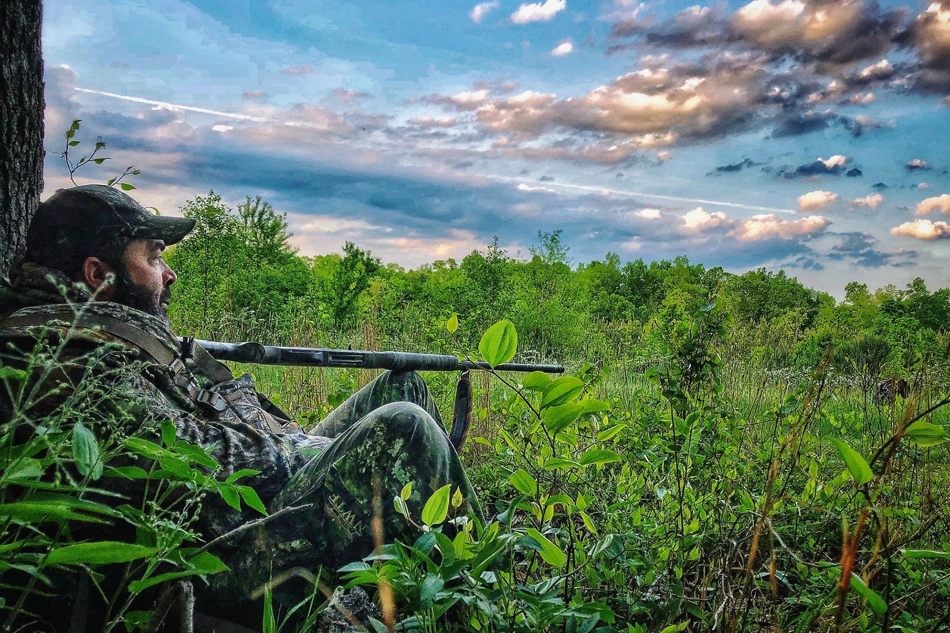Aaron Lewis holding a shotgun on his knee while turkey hunting