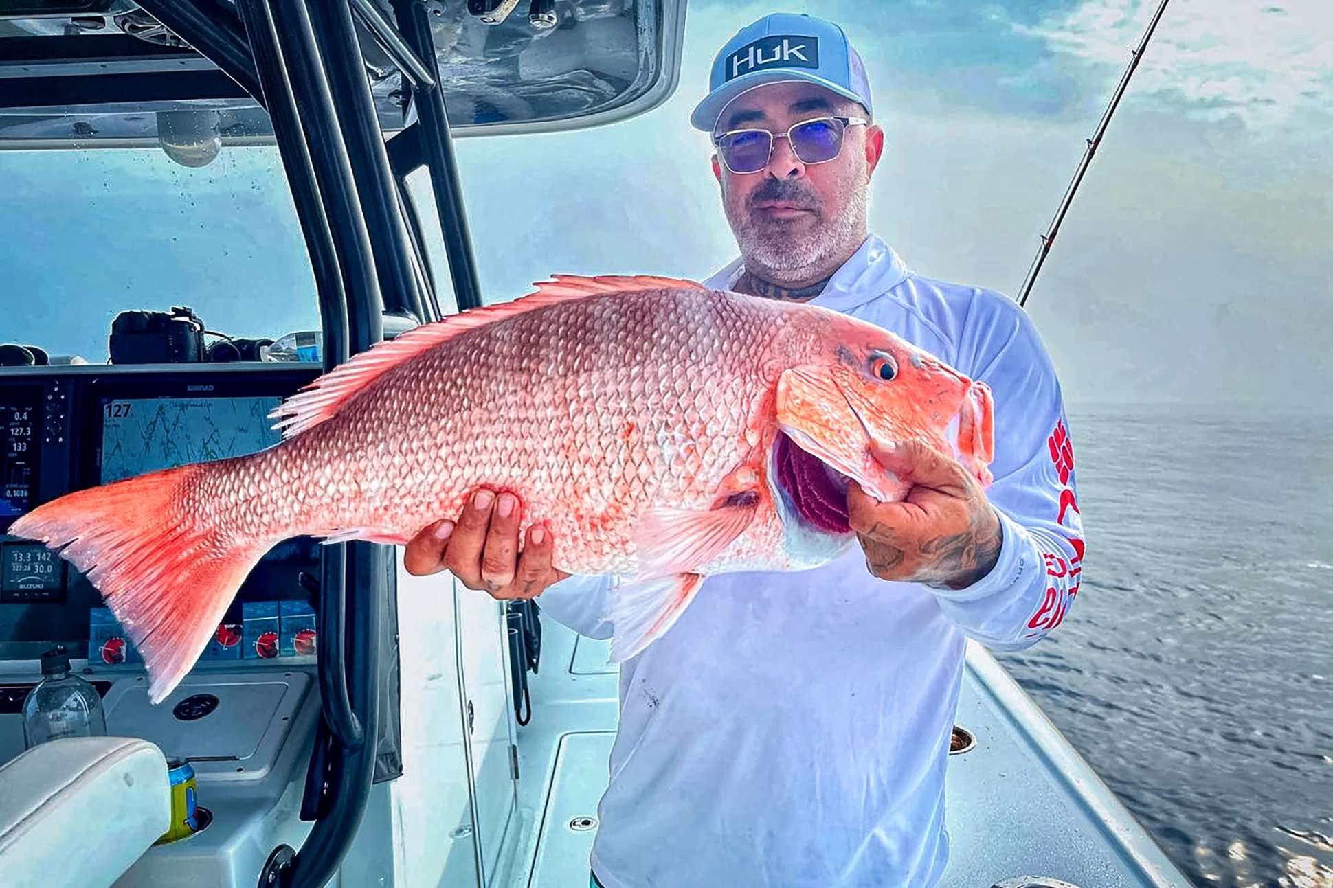 angler on a large boat holding a fush