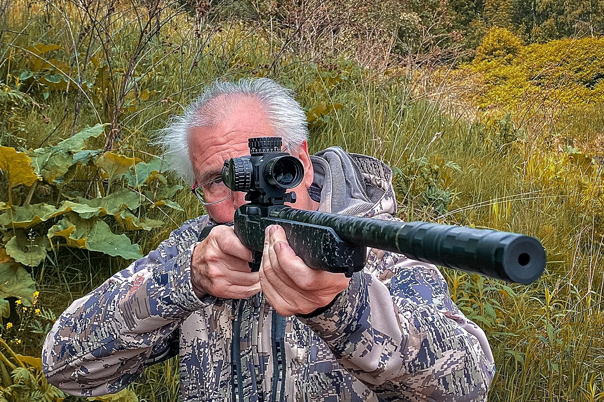 the author aiming the Ruger 10/22 Carbon Fiber rifle with a Trijicon Credo HX 1-8x28 riflescope and a SilencerCo Switchback suppressor