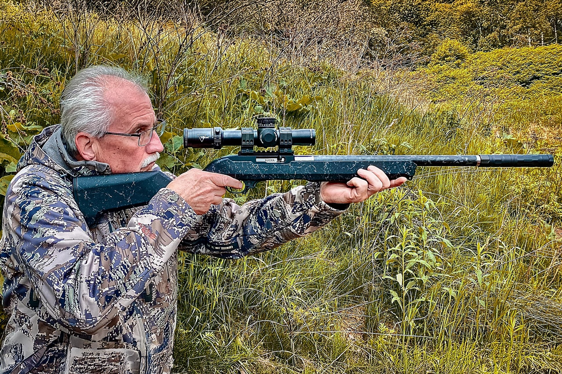 the author aiming the Ruger 10/22 Carbon Fiber rifle with a Trijicon Credo HX 1-8x28 riflescope and a SilencerCo Switchback suppressor