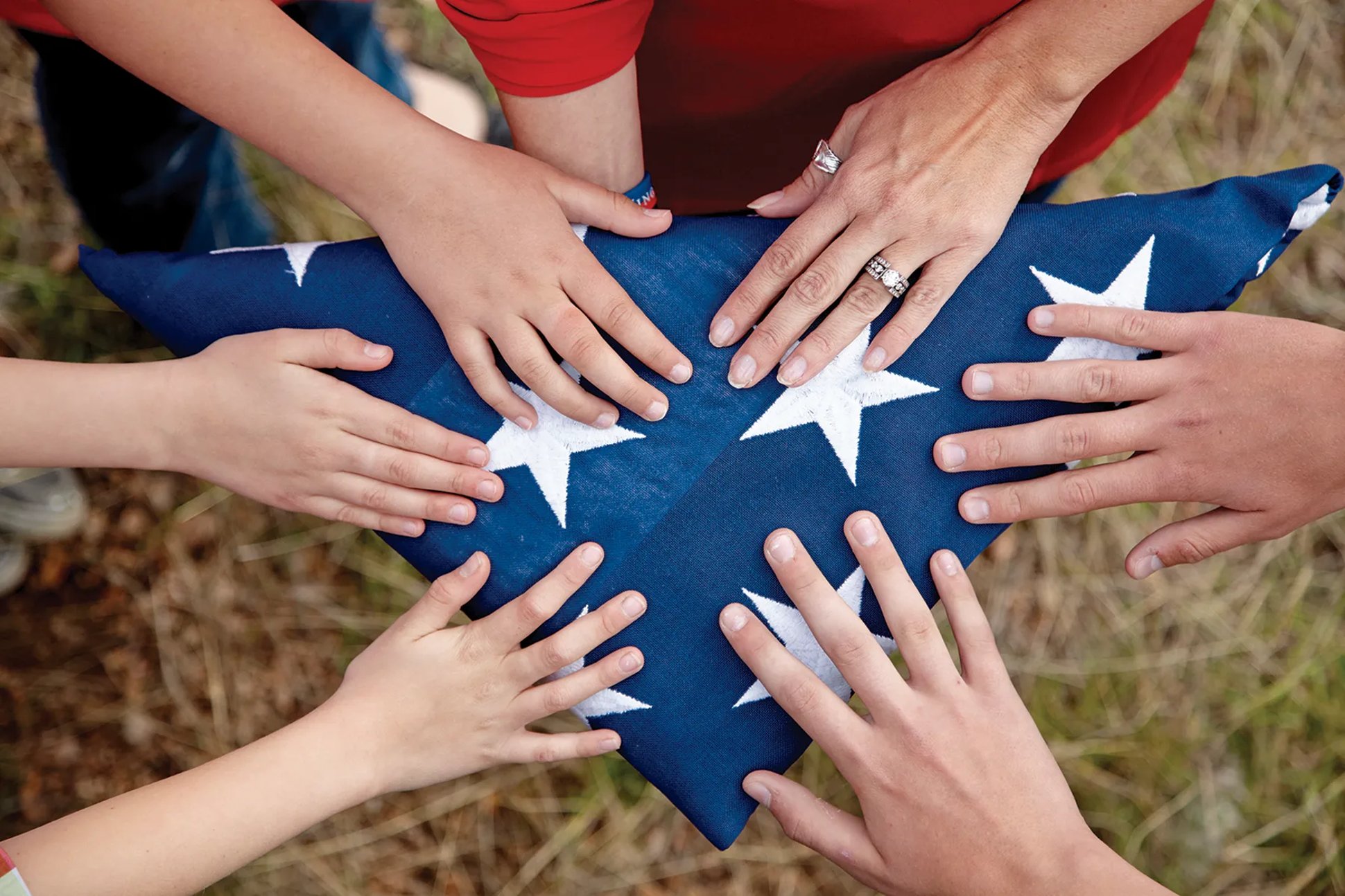 Six people placing their hands on a folded American flag Fold of Honor