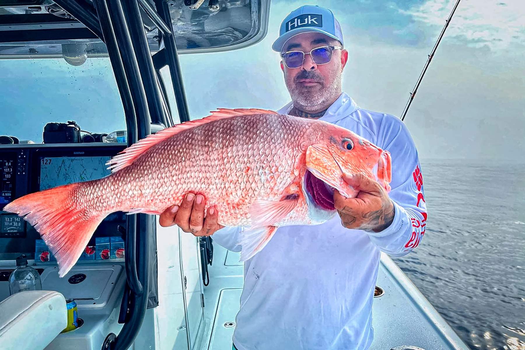 angler on a large boat holding a fush