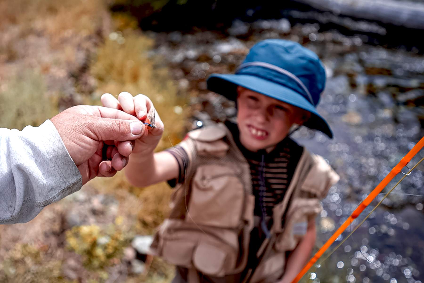 a man handing a young angler a fly