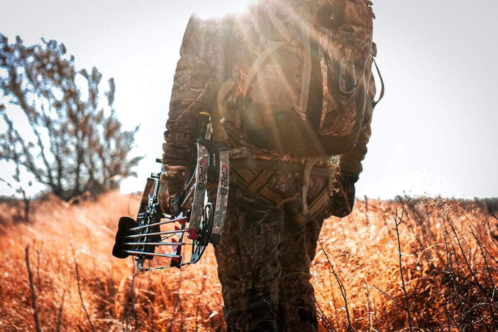 Bowhunter standing in a field with the sun in the background Bowtech