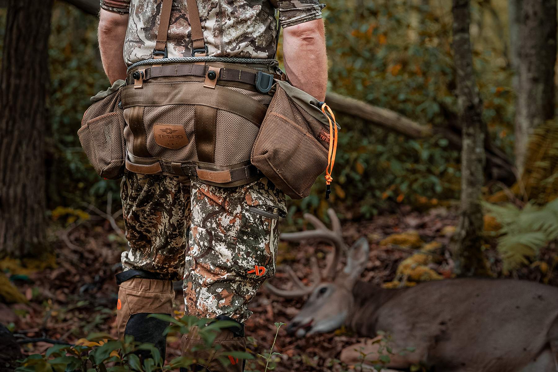 a hunter wearing his hunting saddle next to a nice buck