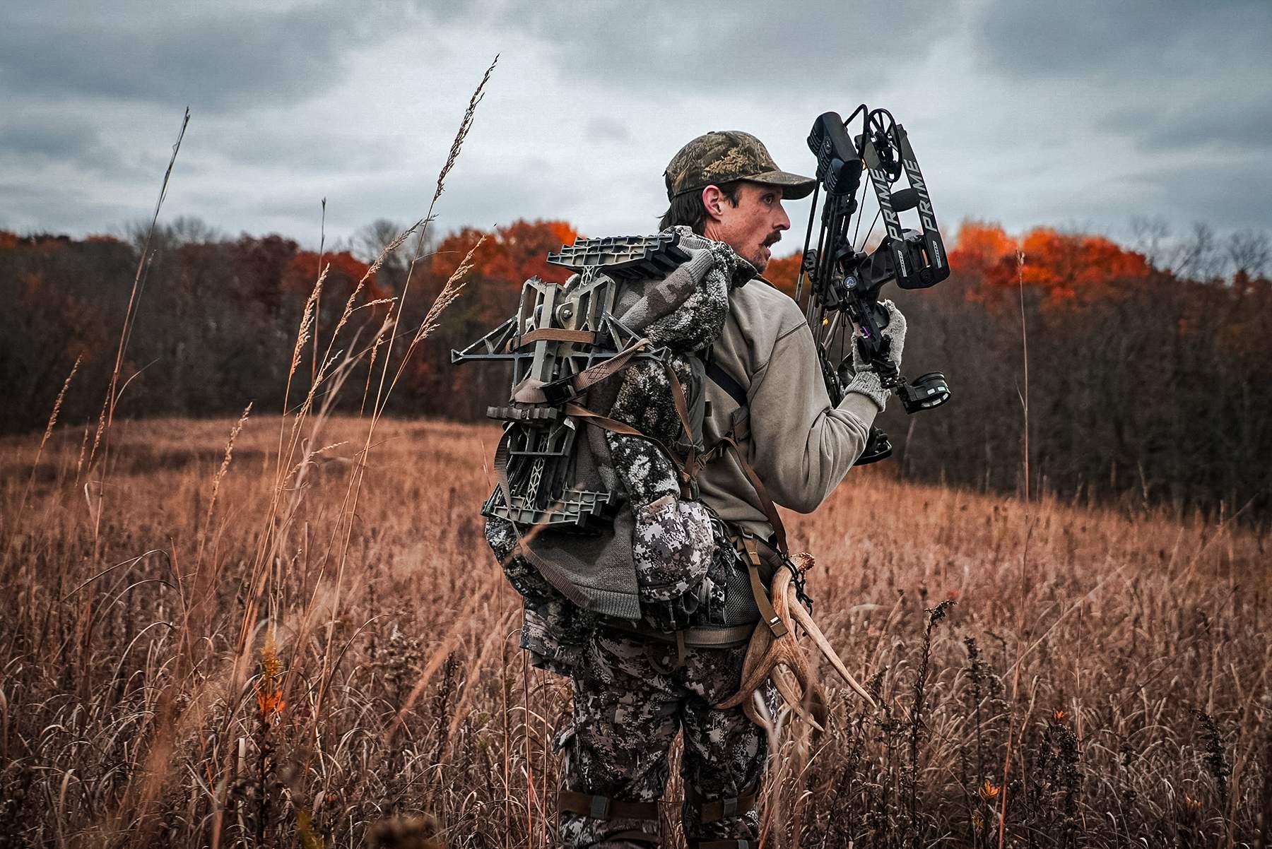 a bowhunter hiking in with his hunting saddle on his back