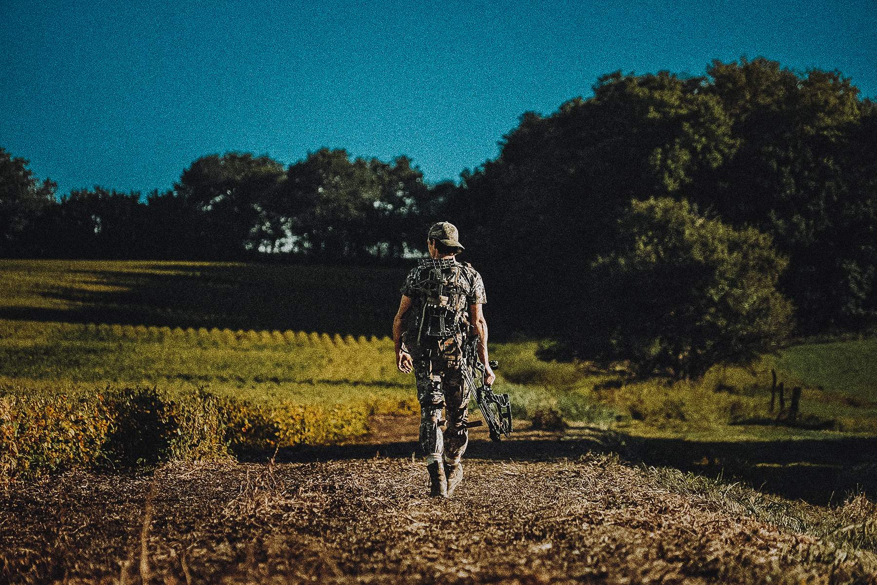 a bowhunter hiking in with his hunting saddle on his back