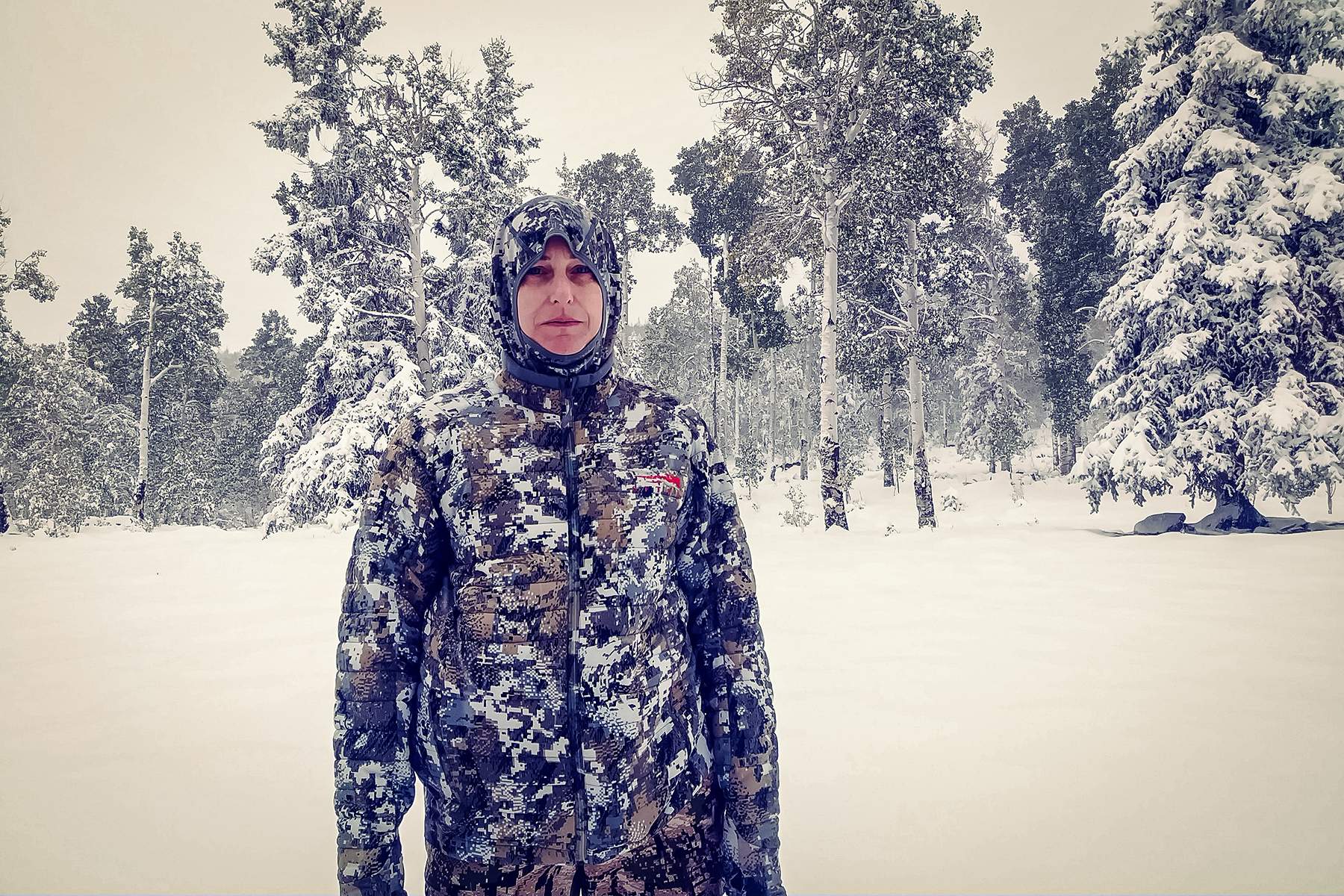 a female hunter in full cold weather hunting gear in the snow